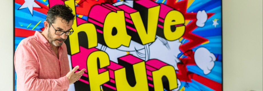Trainer vor buntem Comic-Hintergrund mit "have fun" Schriftzug